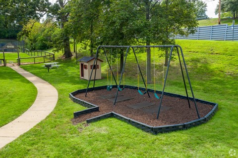 a swing set in a park with a bird house