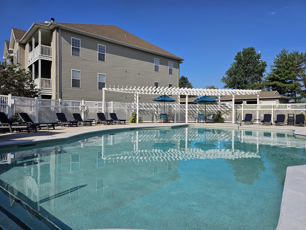a large resort style pool with lounge chairs and a pergola