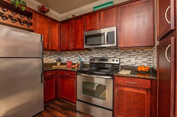 A kitchen with wooden cabinets and a stainless steel refrigerator.