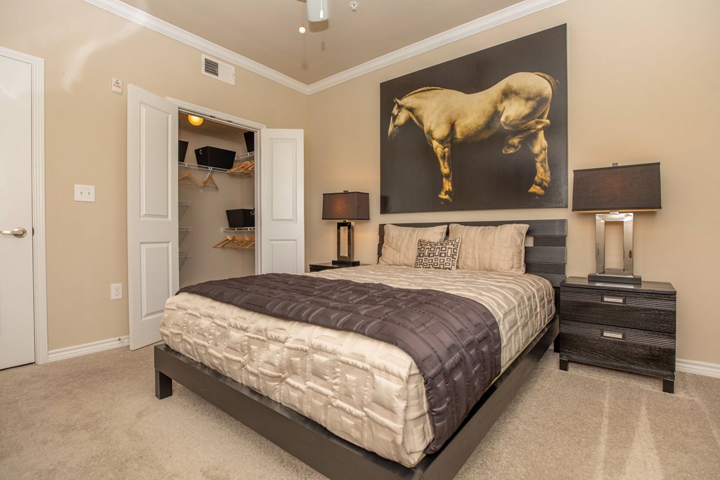 A bedroom with a large bed and a painting of a horse on the wall.