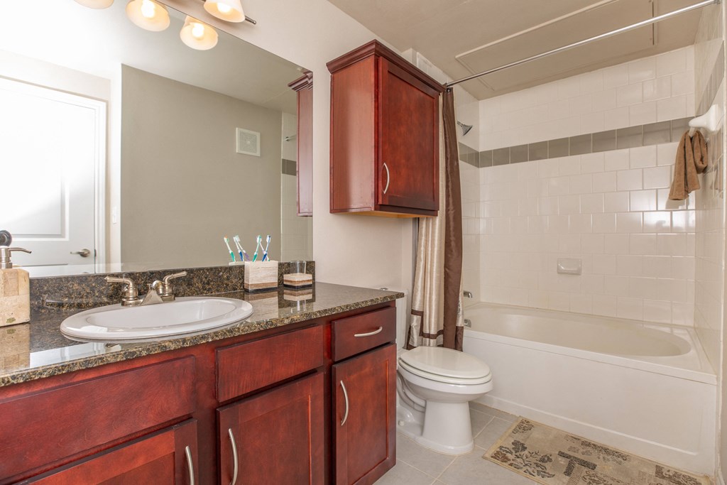 A bathroom with a white tub and a brown vanity.