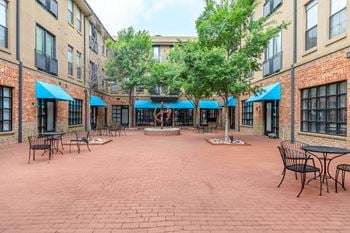 A courtyard with tables and chairs surrounded by brick buildings.