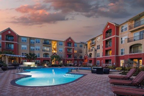 a swimming pool in front of an apartment building at sunset