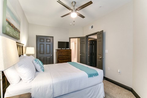 a bedroom with a large white bed and a ceiling fan