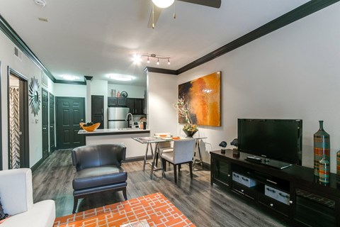 a living room with a tv and a kitchen with a table and chairs
