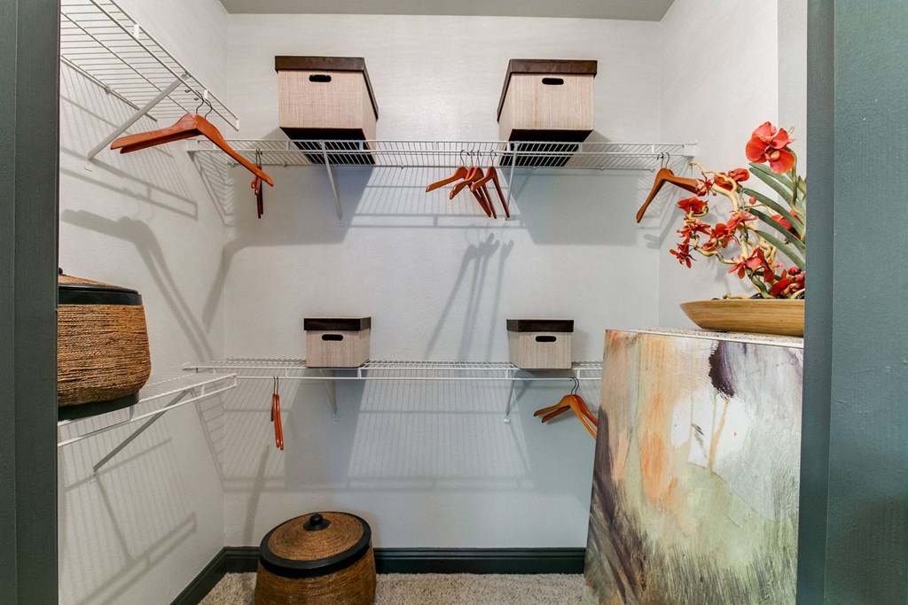 a walk in closet and bins on wire racks and a table with flowers