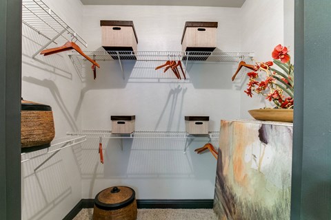 a walk in closet and bins on wire racks and a table with flowers