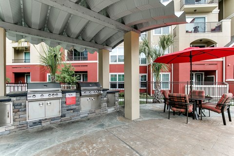 a patio with a grill and tables with umbrellas