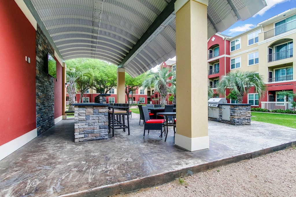 a covered patio with tables and chairs at an apartment building