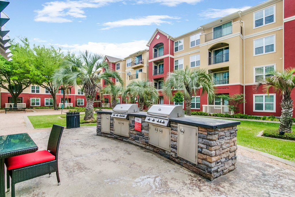 an outdoor patio with a barbecue grill in front of an apartment building