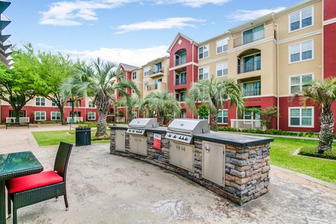 an outdoor patio with a barbecue grill in front of an apartment building