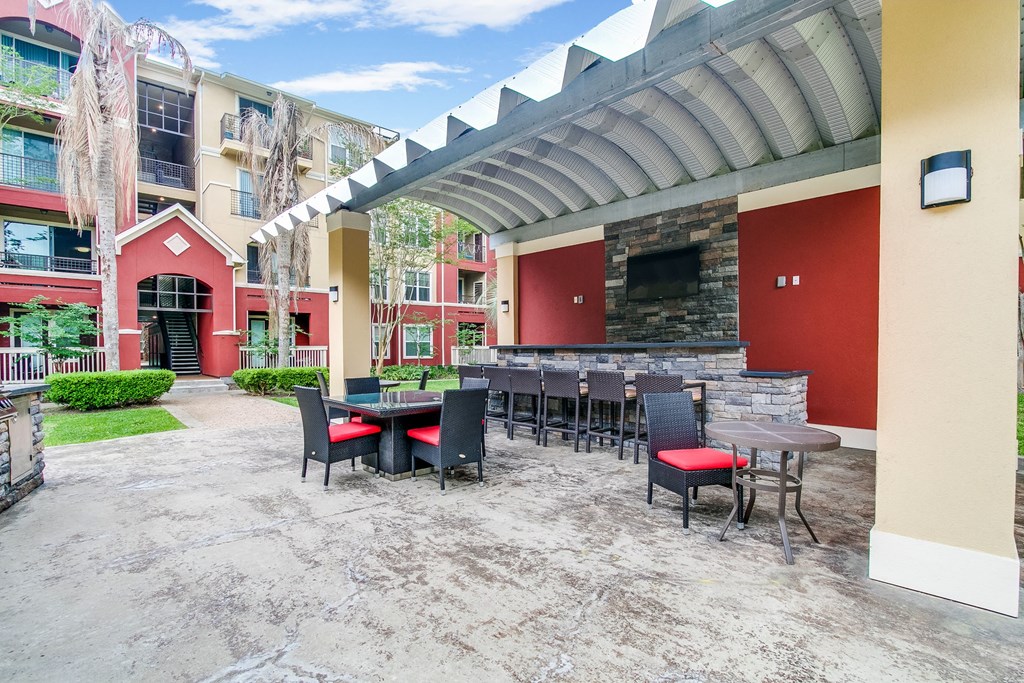 a patio with tables and chairs and a stone fireplace