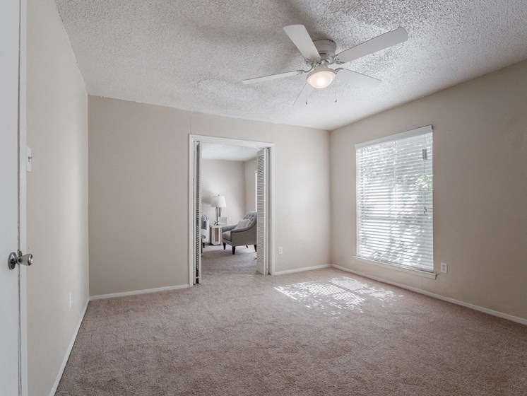an empty living room with a ceiling fan and a window