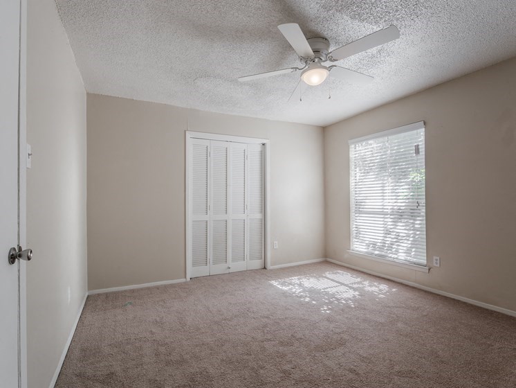 an empty room with a ceiling fan and a window