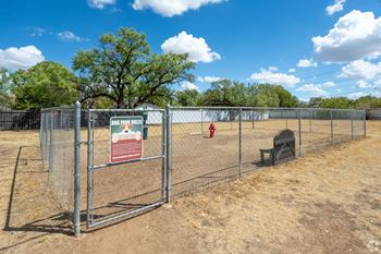 a fenced in dog park with a fire hydrant and a bench