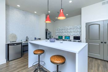 A white kitchen with a bar stool and a dishwasher.