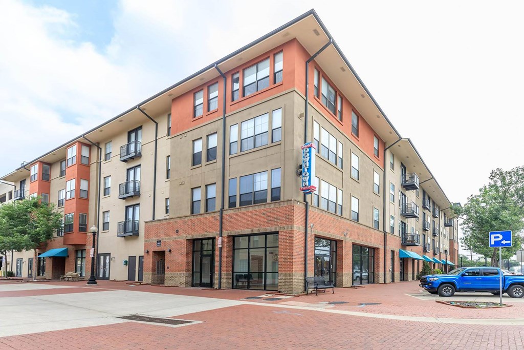 A blue truck is parked in front of a building with a parking sign.