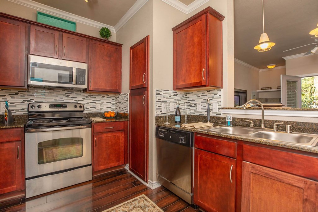 A kitchen with wooden cabinets and a stone backsplash.