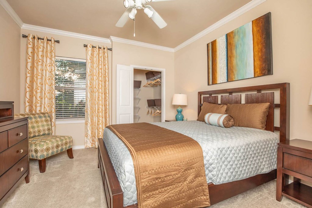 A bedroom with a bed, chair, and a painting on the wall.