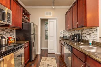 A kitchen with dark wood cabinets and granite countertops.