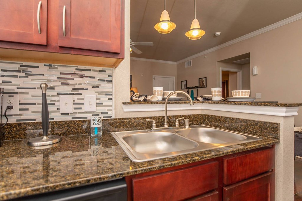 A kitchen with a granite countertop and a stone backsplash.
