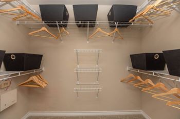 A walk-in closet with clothes hanging on racks and shelves.