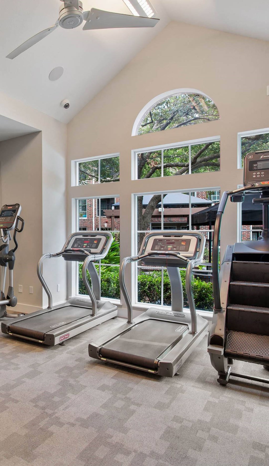 a gym with cardio machines and a large window