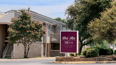 A sign for Bel Air Apartments stands in front of a building.