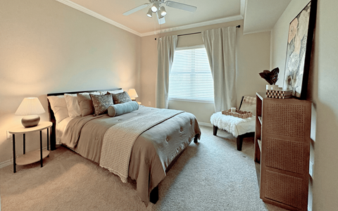 A bedroom with a large bed and a small table with a lamp on it.