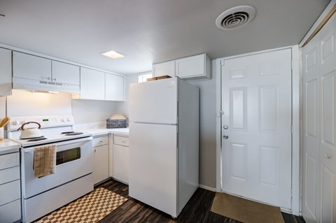A white kitchen with a refrigerator and a stove.
