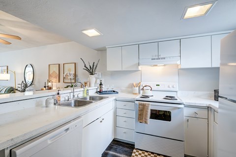 A white kitchen with a sink, stove, and refrigerator.