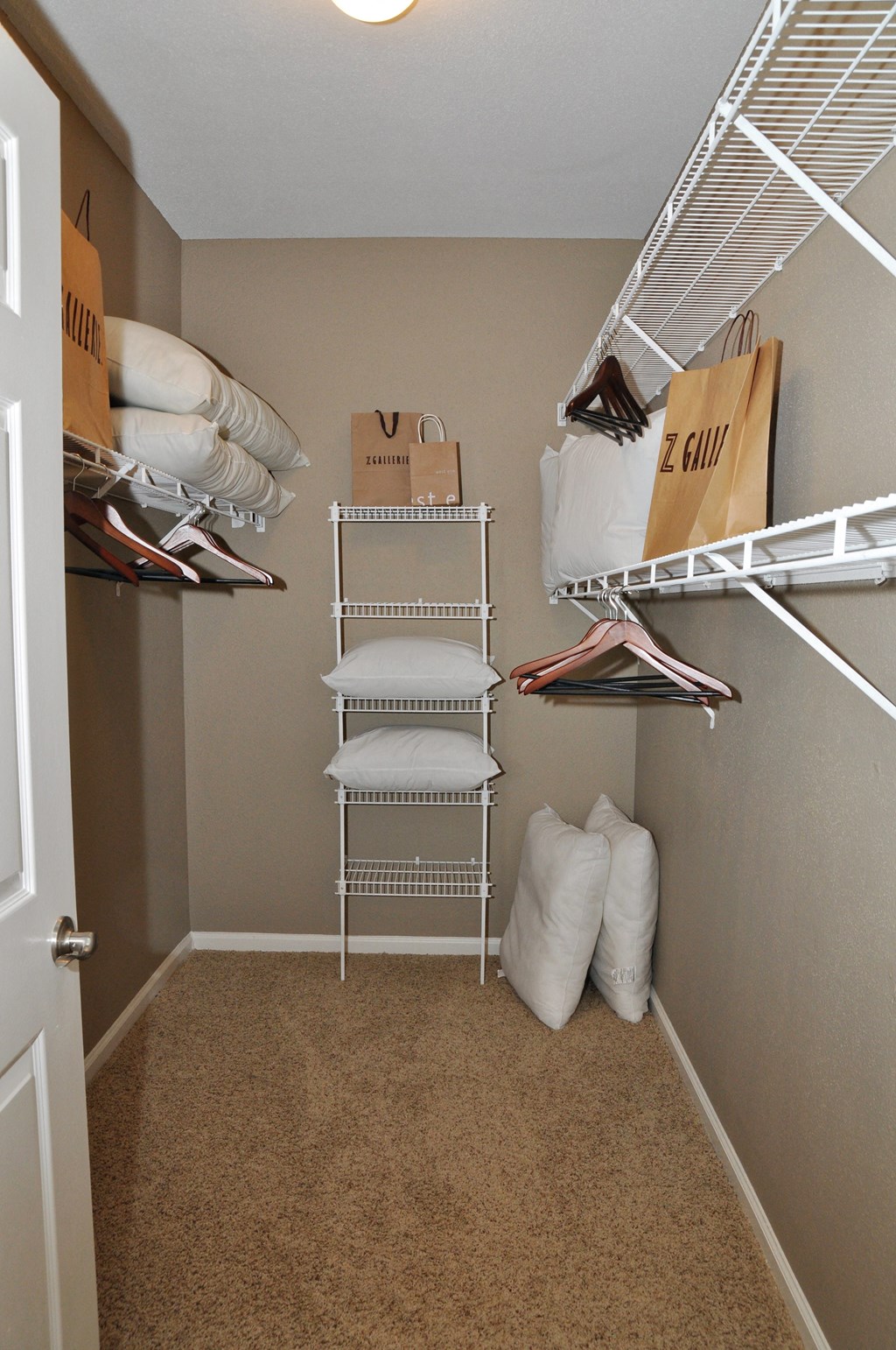 a walk in closet with a rack for clothes and a pile of pillows