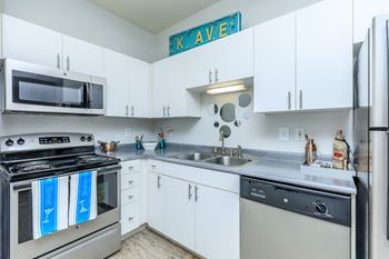 A kitchen with white cabinets and a stove top oven.