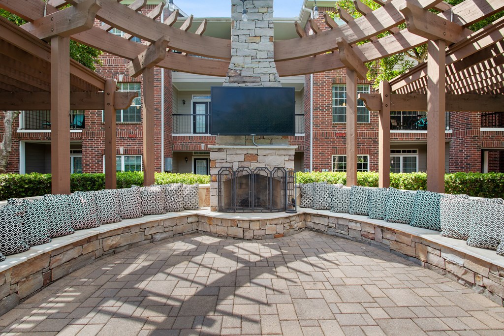 a patio with a stone fireplace and a large wooden structure