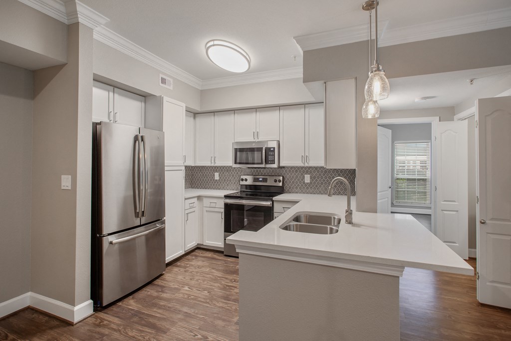 a white kitchen with stainless steel appliances and a white counter top