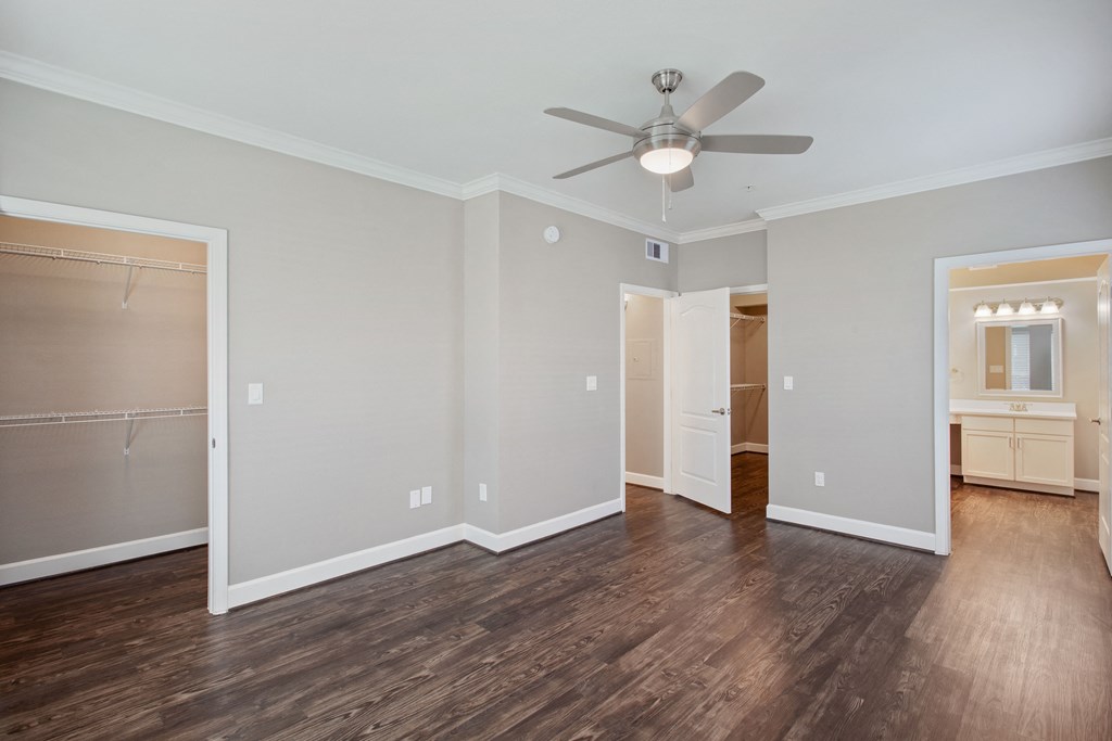 an empty living room with a ceiling fan and a closet