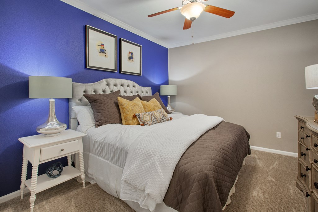 a bedroom with a bed and a blue wall and a ceiling fan