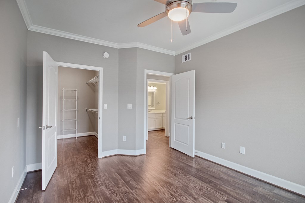 an empty living room with wood floors and a ceiling fan
