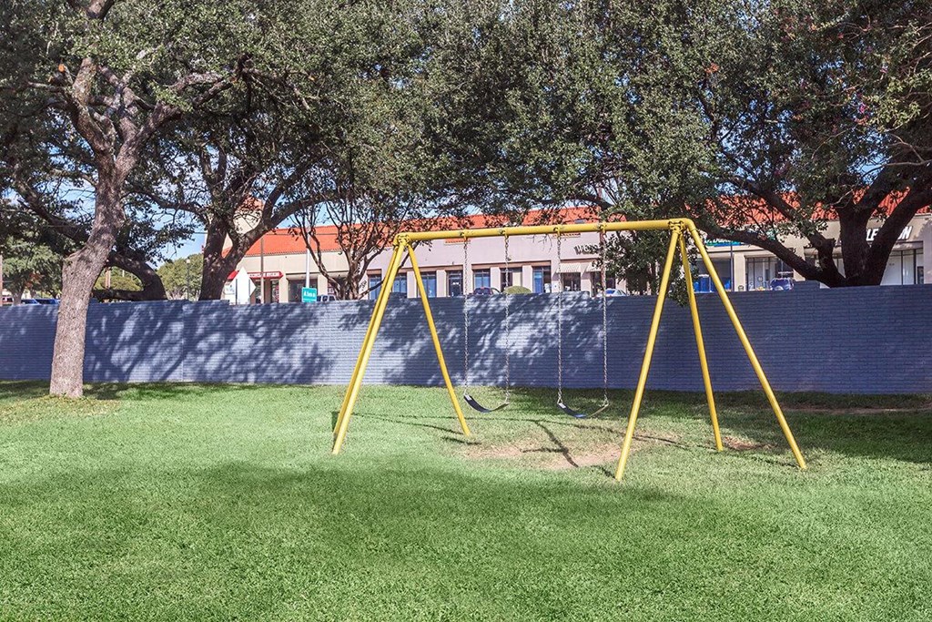 a yellow swing set in a playground with trees