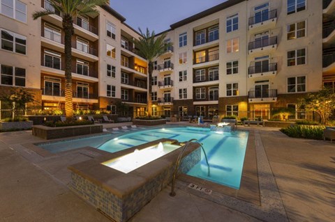 an apartment pool in front of an apartment building at night