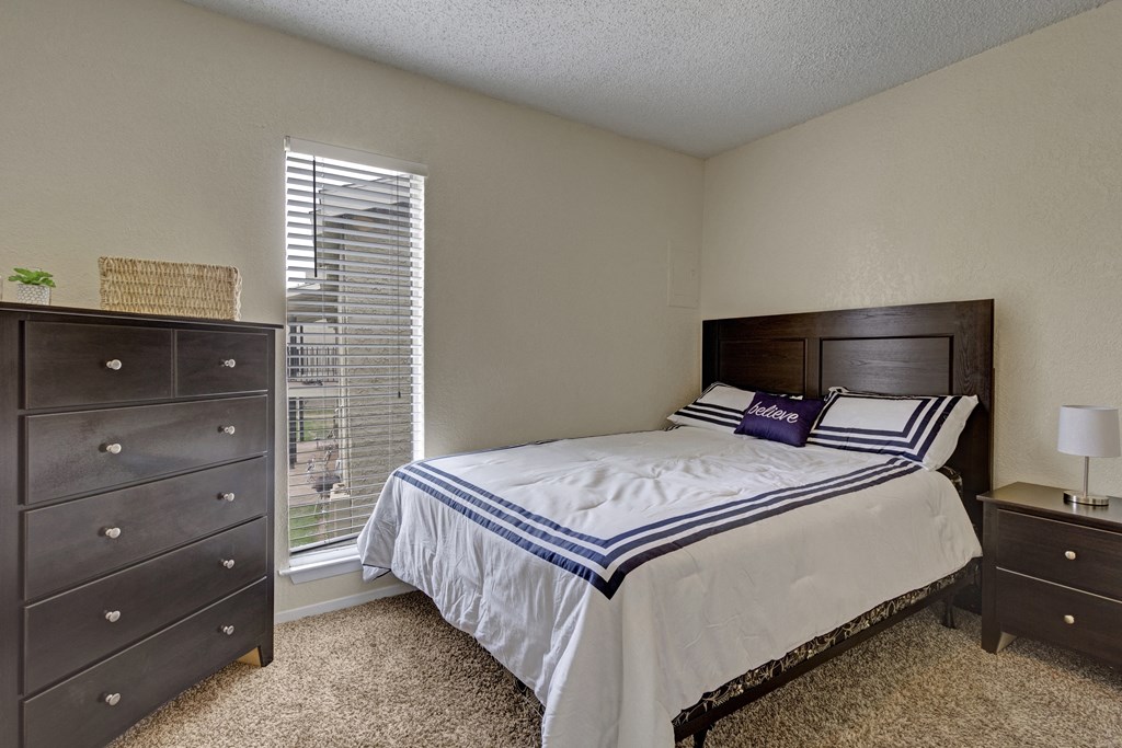a bedroom with a bed and a dresser and a window