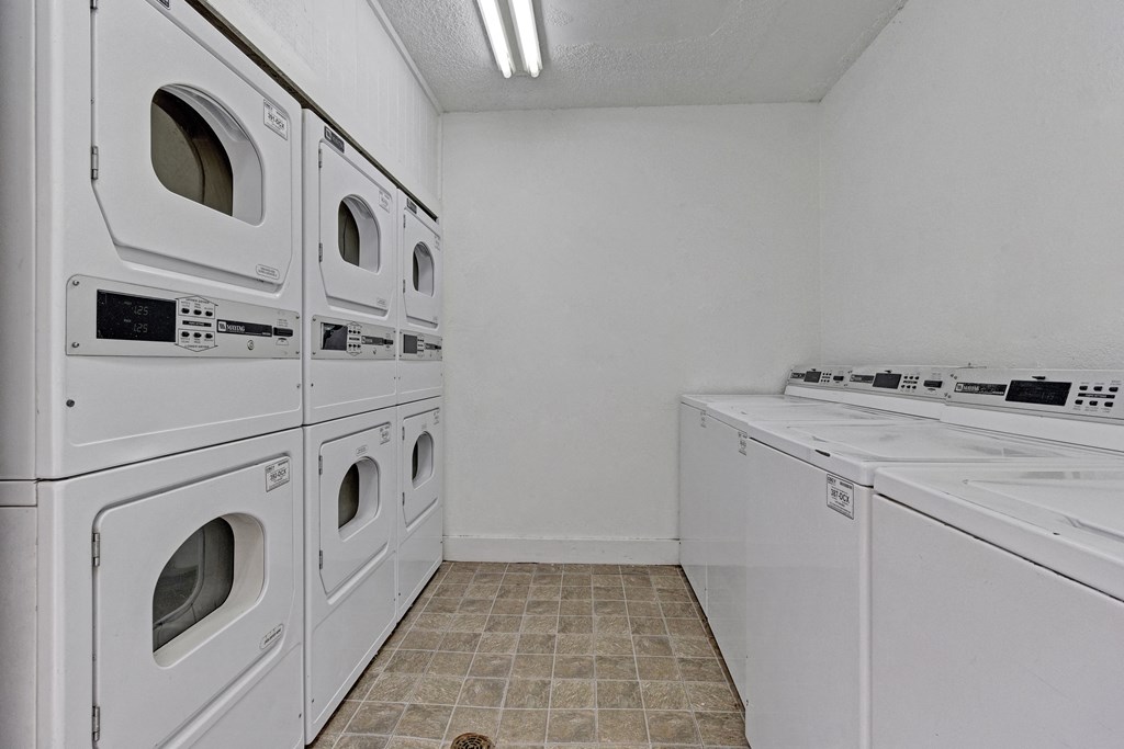 an empty laundry room with white washes and dryers