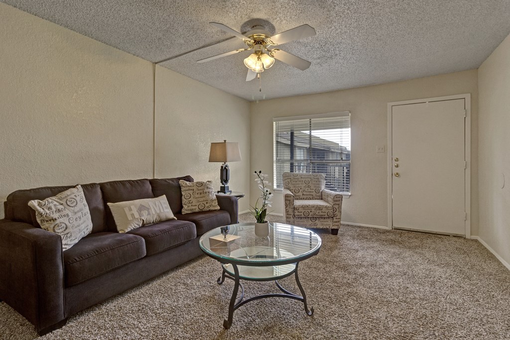a living room with a couch and a coffee table and a ceiling fan