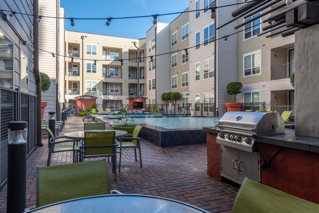 a patio with tables and chairs and a pool in front of an apartment building