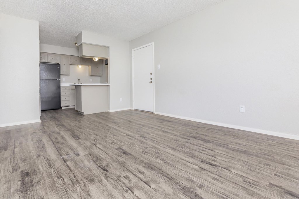 the living room and kitchen of an apartment with wood flooring