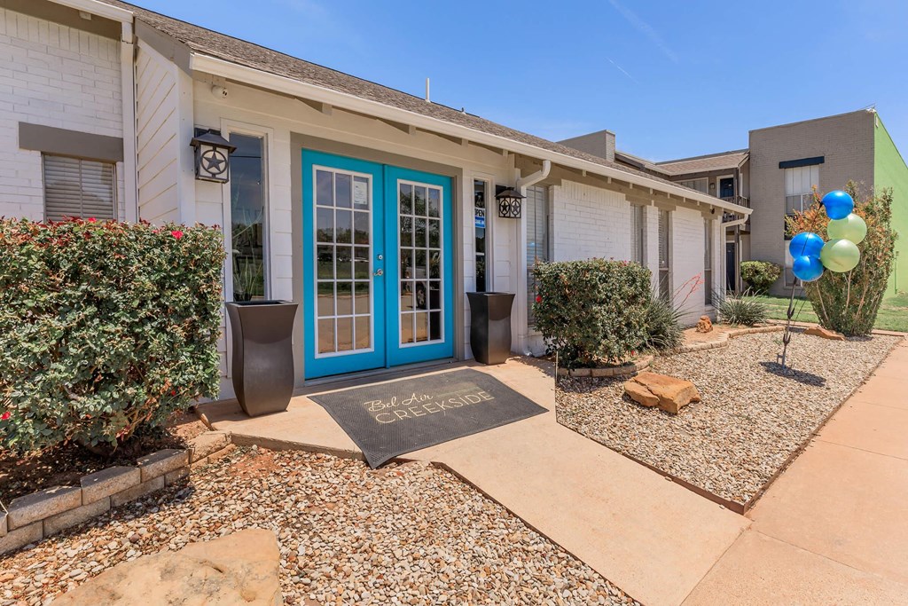 the front of a house with a blue door and a sidewalk with plants and balloons