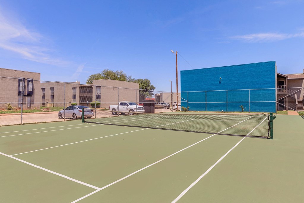 a tennis court in front of a building with a blue wall