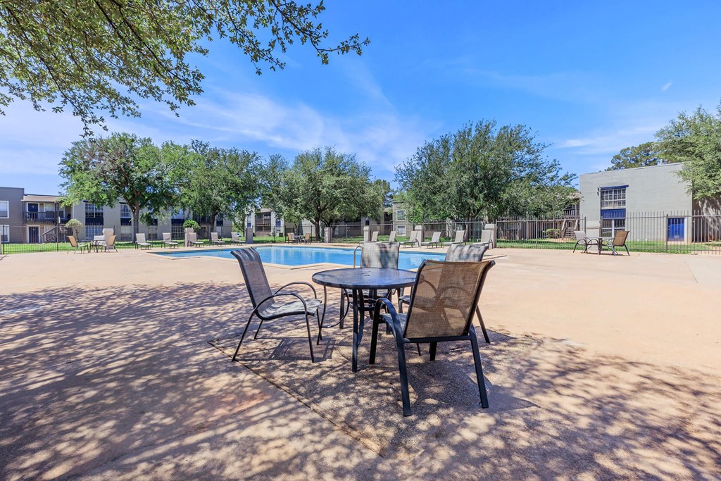 our apartments have a patio with a table and chairs and a pool