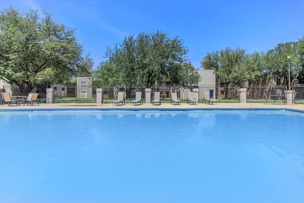 a large pool with trees and chairs around it