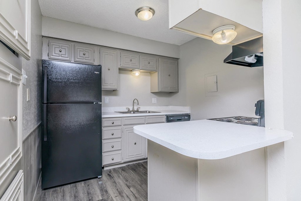 a kitchen with white counter tops and a stainless steel refrigerator